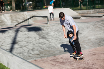 Father teaching son skateboarding at skateboard park © Cavan for Adobe