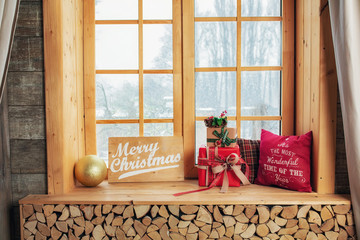 Cozy and frost winter day: christmas decoration on wood windowsill and snow landscape from outside.