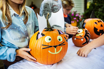 Obraz premium Children holding decorated pumpkins at table during Halloween