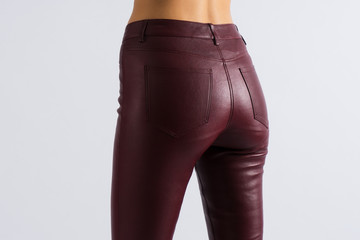 Beautiful slim booty girl. Leather burgundy skinny pants with pockets. Close up view on sexy ass...