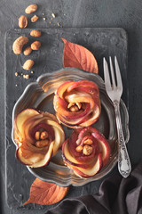 Three homemade puff pastries with rose shaped apple slices on metal plate, flat lay