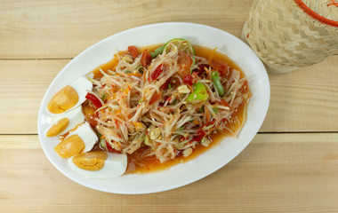 Papaya Salad with Blue Crab. Thai style spicy food, Som Tum in a green plate on wood floor table, Thai foods. Top view Copy Space..