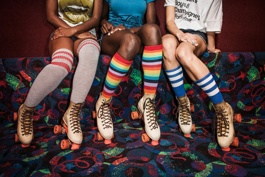 Low section of women wearing roller skates sitting on multi colored sofa
