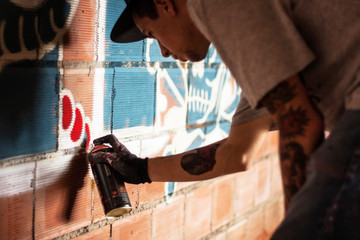 Side view of man spraying graffiti on brick wall © Cavan for Adobe