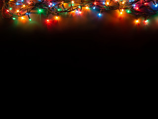 Christmas background with lights and free text space. Christmas lights border. Glowing colorful Christmas lights on black background. New Year. Christmas. Decor. Garland.