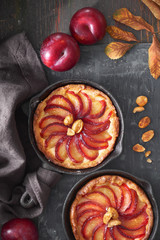Homemade crumble tarts with plum slices baked in small iron skillets