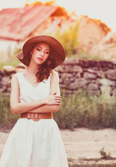 Style girl in hat and white dress at countryside in village