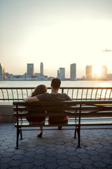 Rear view of couple sitting on bench at promenade by river in city © Cavan for Adobe