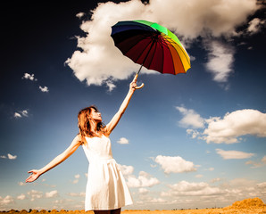 Style redhead girl in white dress with umbrella at countryside on cloudy sky background