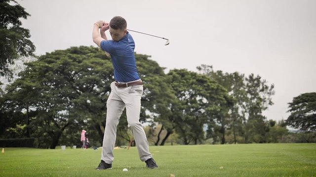 Golfer hitting ball on green grass, slow motion