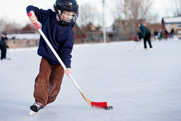 Naklejka premium Child playing ice hockey on rink