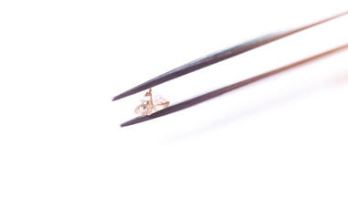 natural transparent diamond in the form of a pyramid in tweezers
