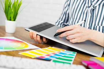 Young graphic designer woman using digital graphic tablet while working at office