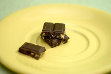 Stack of chocolate pieces, with hazelnuts. Selective focus. 