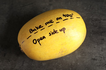 Ripe spaghetti squash with cooking instructions on gray table