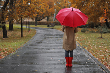 Woman with umbrella in autumn park on rainy day