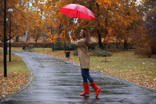 Woman with umbrella taking walk in autumn park on rainy day