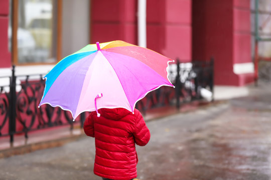 Little girl with umbrella in city on autumn rainy day