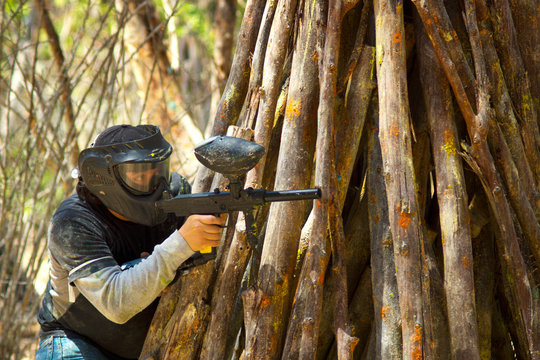 Paintball shooter hiding behind logs