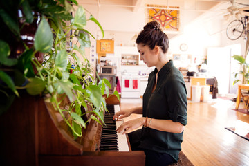 Side view of woman playing piano at home on sunny day © Cavan for Adobe