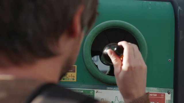 Young man male hand dropping glass plastic bottle into recycle bin and there are waste separation bin for different kind of garbage to safe environment. pollution or waste management business concept.