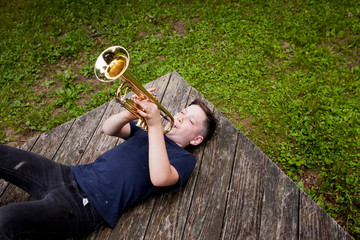 High angle view of boy playing trumpet lying on porch © Cavan for Adobe