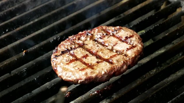 Single hamburger is cooking on the grill