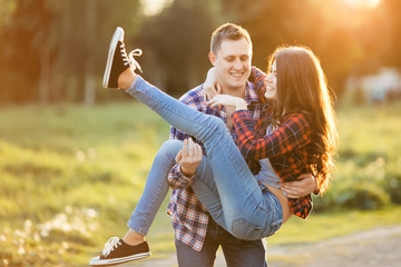 Couple in love. The guy is holding the girl in her arms in the park.