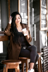 Beautiful girl drinks coffee, sitting in a cozy cafe.