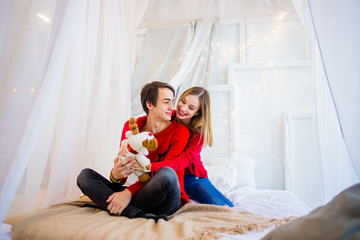 Exquisite couple in red sweaters posing on the bed