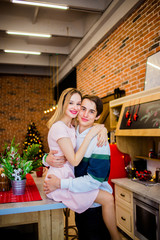 Lovely girl sitting on a table hugging with a guy standing near to her
