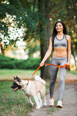 Sports woman walking with dog in the park.