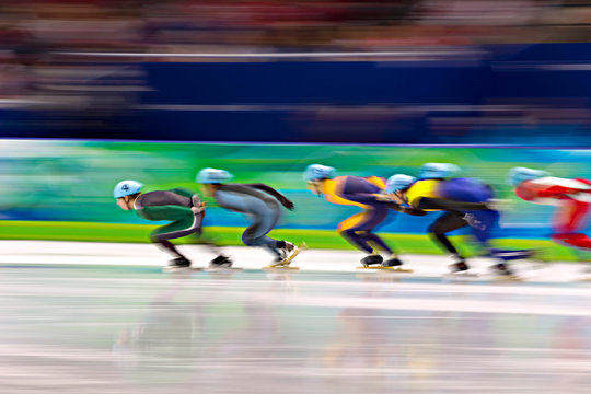 Side view of ice-skaters in skating ring