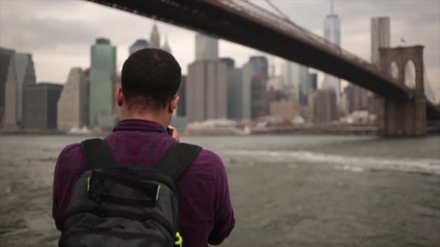 Tourist in purple shirt takes photo of the New York skyline on his smart phone