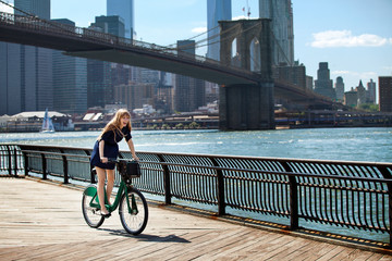 Woman cycling on promenade against Brooklyn Bridge © Cavan for Adobe