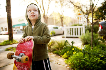 Boy looking away while holding skateboard © Cavan for Adobe