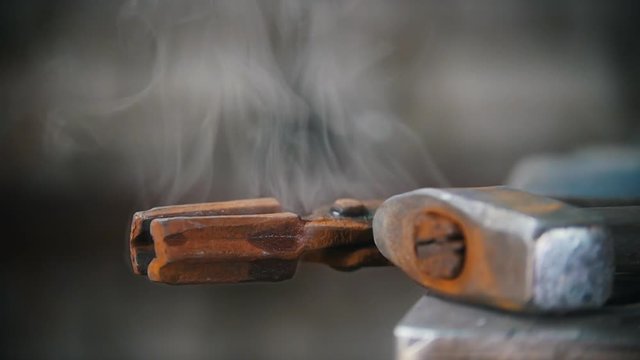 Water evaporates from the forceps. Blacksmith workroom. Close up