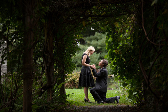 Man proposing to woman on grassy field