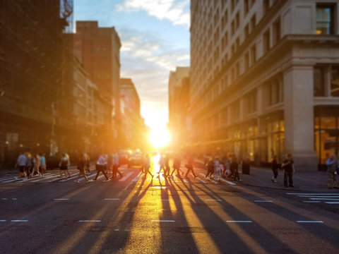 People Cross Busy Intersection On 23rd Street In Manhattan New York City With The Colorful Light Of Sunset Casting Long Shadows