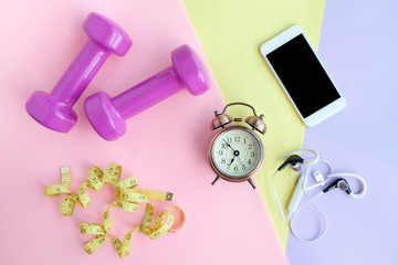 Fitness equipment, Dumbbell and earphone , water bottles on colorful Pink, yellow and blue background .Health and Fitness Concepts
