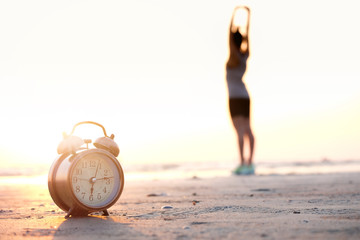 Morning of a new day, alarm clock woman playing yoga and stretching muscles on the beach sunlight...