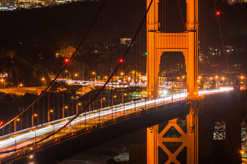 Night view of one of the towers of the Golden Gate Bridge with bright traffic, San Francisco, California; long exposure