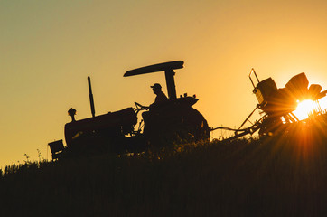 Trator plantando no p&ocirc;r do sol 