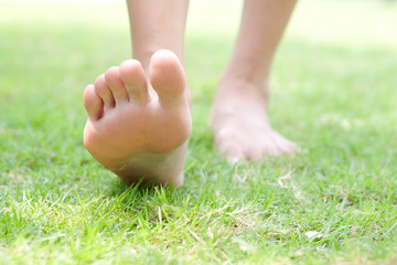 Leg of woman is on the ground. She is about to walk down the grass to exercise in the morning. Health and Relaxation Concepts