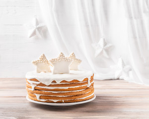 Biscuit cakes sprinkled with white cream are decorated with round candies chips and star-shaped cookies on a table on a light background. Copy space.  Festive New Year and Christmas concept.