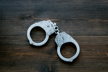Metal handcuffs on dark wooden background top view space for text