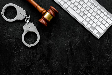 Arrest of a hacker for cyber fraud concept. Handcuff near keyboard and judge gavel on black background top view copy space