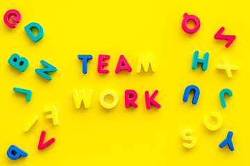 Teamwork training concept. Text teamwork lined with colored letters near toy letters on yellow background top view copy space