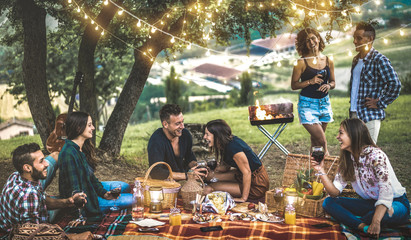 Happy friends having fun at vineyard after sunset - Young people millennial camping at open air picnic under bulb lights - Youth friendship concept with young people drinking wine at barbecue party - obrazy, fototapety, plakaty