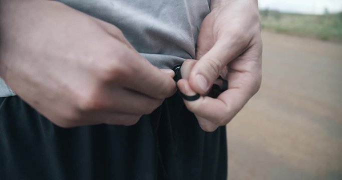 Hands tying waist string on black running shorts 
